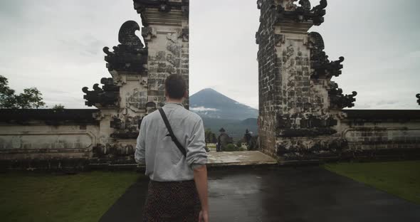 Dolly Medium Shot of a Man Walking Towards Gates of Heaven Temple Gates in Pura Penataran Agung