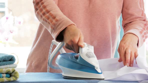 Female Hands Ironing Clothes with Iron on Ironing Board