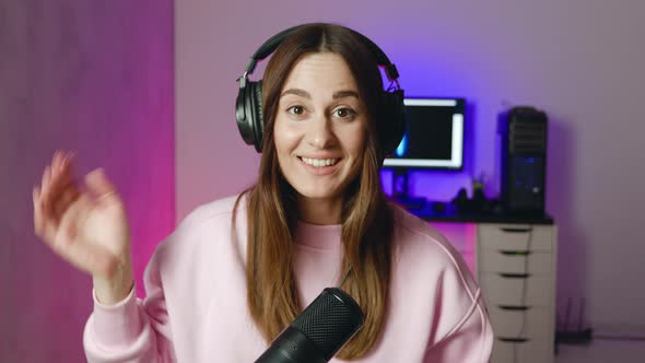 Young Female in Headphones Rodecaster Making Audio Podcast at Home Neon Studio Background