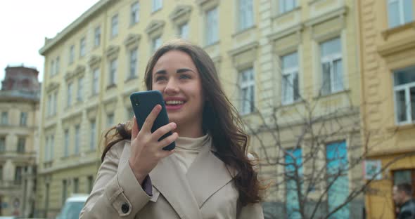 Woman Using a Smartphone Voice Recording Function Online in the City Street, Voice Message. Girl