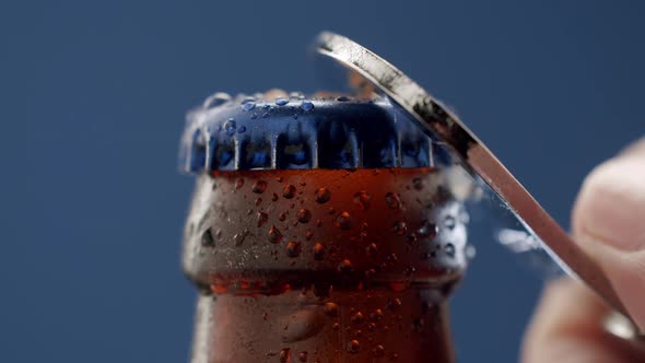 One Hand Opens the Beer Bottle on Blue Background
