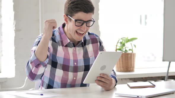 Young Man Celebrating Success on Tablet