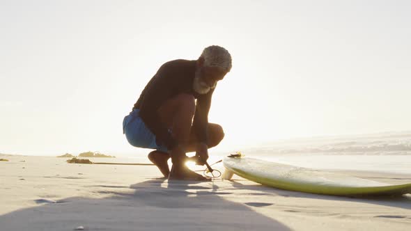 Senior african american man preparing before surfing on sunny beach