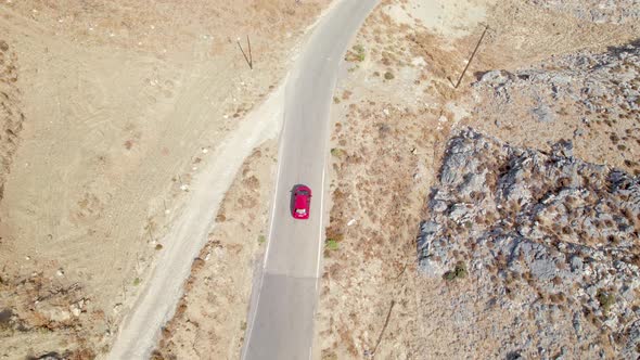 Cinematic road landscape. Yellow sand and rocks, moving car. Aerial drone flight top down shot.