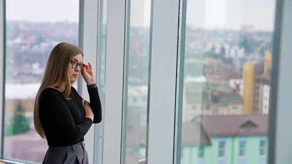 woman in eyeglasses while standing by the window