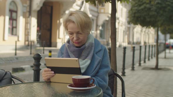 Elderly Woman Using Tablet Surfing Internet Shopping Online Outdoors