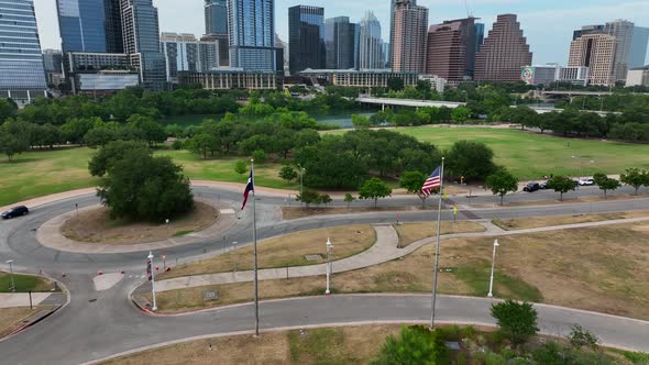 American and Texas flags wave in Austin, Texas breeze in front of the city's skyline. Walkable infra