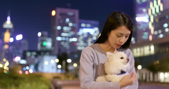 Woman playing with her dog in city at night