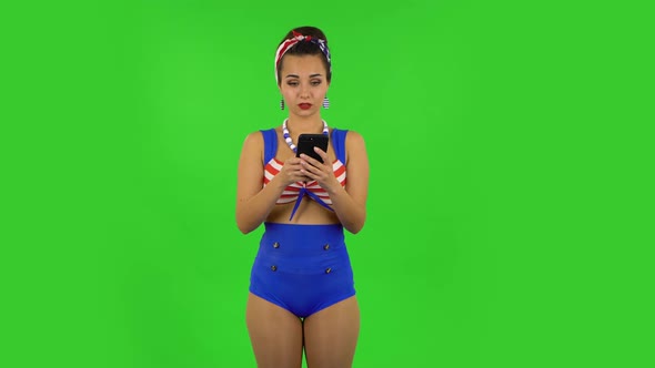 Beautiful Girl in a Swimsuit Is Texting on Her Phone and Rejoicing. Green Screen