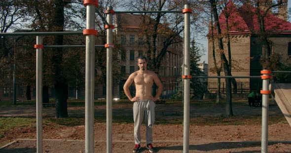 Young Man Is Standing Near Horizontal Bars After Training in Sunny Weather 