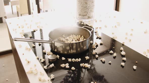 Pan on Stove with Popcorn Popping Out of Pan and on the Kitchen Counter