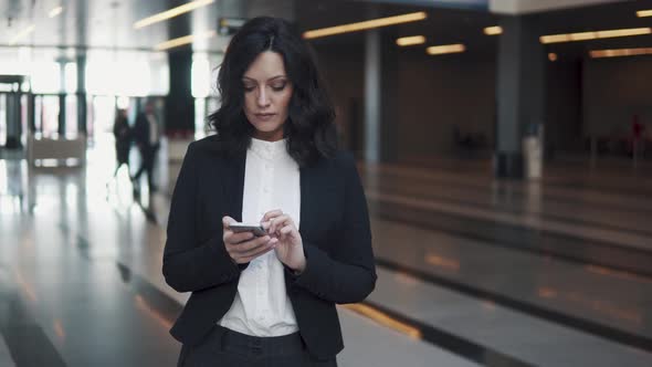 a Woman in a Business Suit Walks Through the Lobby of a Modern Office Building. Business Woman Uses