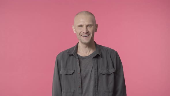 Handsome Middleaged Bald Man with Bristle Looking Curious with Pleased Grin at Camera and Start