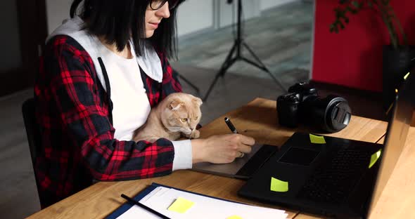 Creative Female Photographer with Cute Cat Using Graphic Drawing Tablet and Stylus Pen
