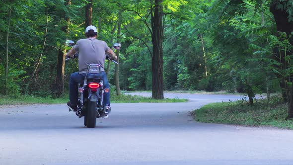 ForestMan Riding A Motorcycle Through The Woods. He moves away from the camera. Bike1