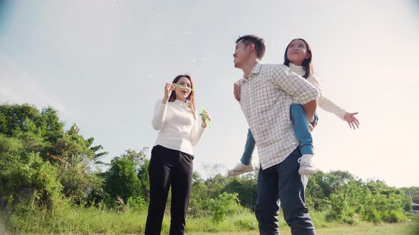 happy family life concept. Asian parents and the little girl enjoying and fun playing soap bubbles.