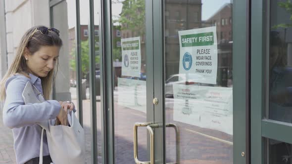 Girl reads sign with safety first written on it, covers her face with mask