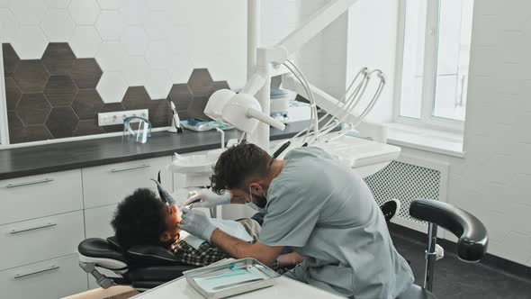 Caucasian Dentist Treating Cavity of Boy