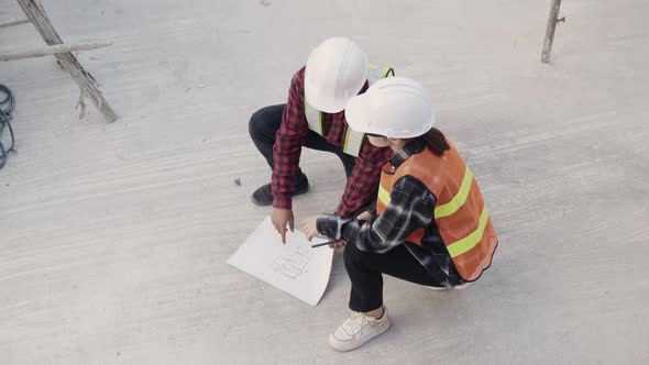 Architect and client discuss help create plan with blueprint of the building at construction site