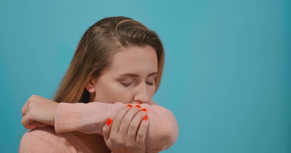 Lady with Long Loose Fair Hair Coughs Into Upper Sleeve