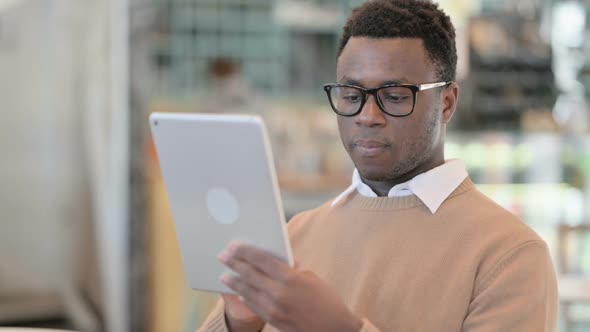 Attractive Creative African Man Using Tablet in Cafe