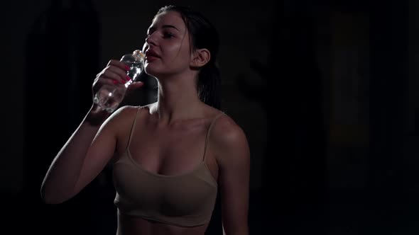 Medium Shot Portrait of Happy Caucasian Sportswoman Drinking Water in Slow Motion Standing in
