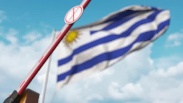 Closing Barrier with STOP CORONAVIRUS Sign at Flag of Uruguay