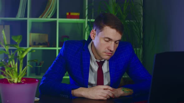 Tired Businessman Sleeping Sitting at Table in Office