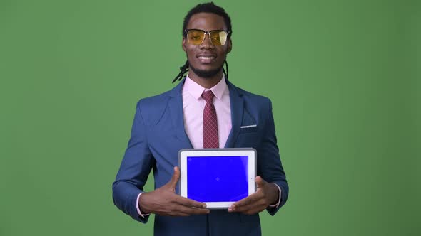 Young Handsome African Businessman with Dreadlocks Against Green Background