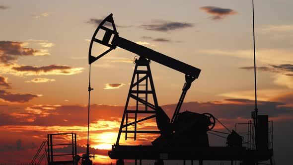 Silhouette Working Oil Pump in Deserted District at Sunset