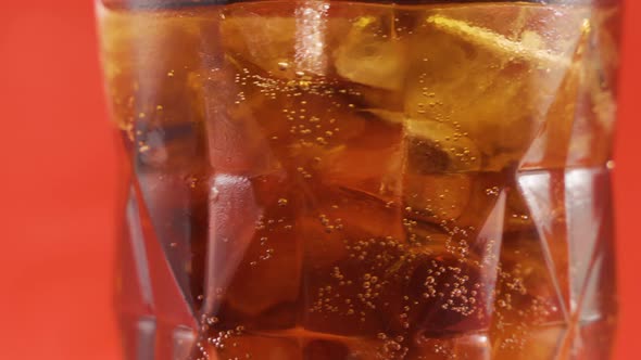 Ice cubes and cola in a swirling glass.