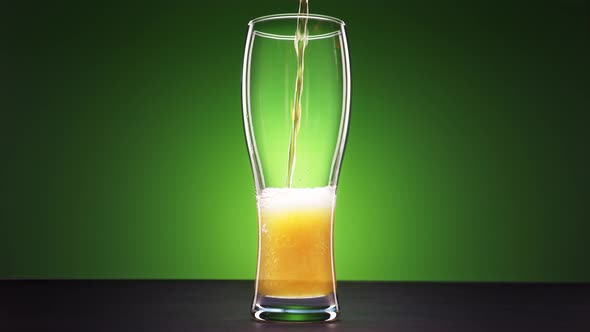 Pouring Beer Drink Into Glass on Green Background