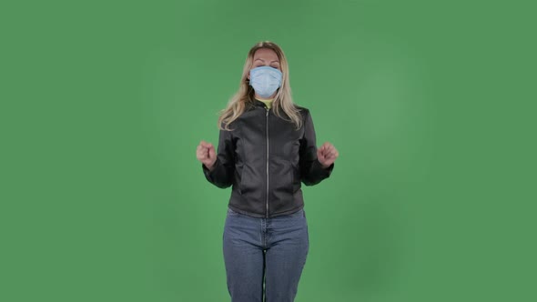 Portrait of Beautiful Young Woman in Medical Mask Is Looking at Camera and Pointing Up Fingers