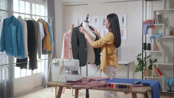 Female Designer With Sewing Machine Wearing Business Jacket On A Mannequin While Designing Clothes