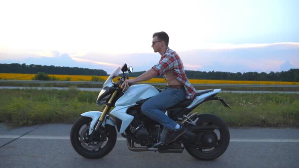 Young Man Riding on a Modern Sport Motorbike. Handsome Motorcyclist in a Shirt and Glasses Driving