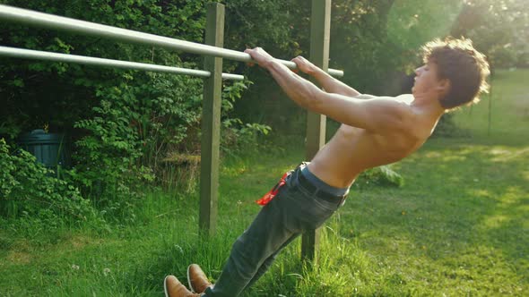 Fit young man topless doing pull up exercise on parallel bars with retracted scapula shoulder blades