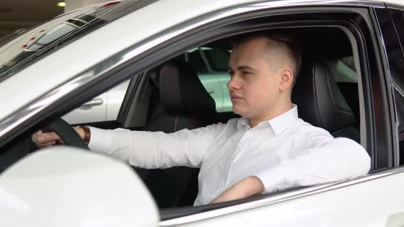 Portrait of a Young Confident Man Sitting in a New Car at a Car Dealership