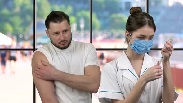 Young Nurse Filling Syringe From Medicine Vial To Vaccinate Her Patient