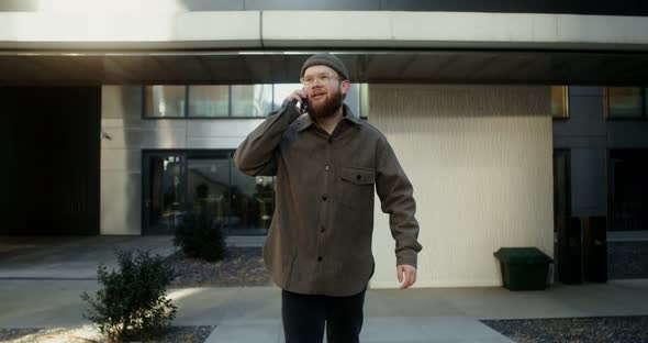 A Young Man is Typing on a Mobile Phone While Walking Around the Business Center