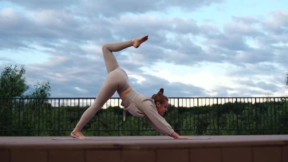 Front View of Young Flexible Woman Doing Three Legged Downward Facing Dog Pose Practicing Yoga