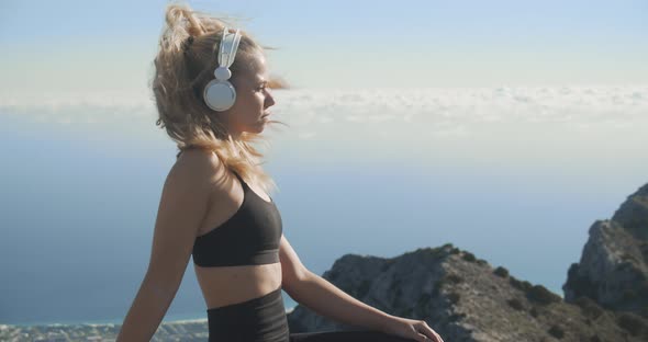 Young Woman Listening To Headphones On Mountaintop