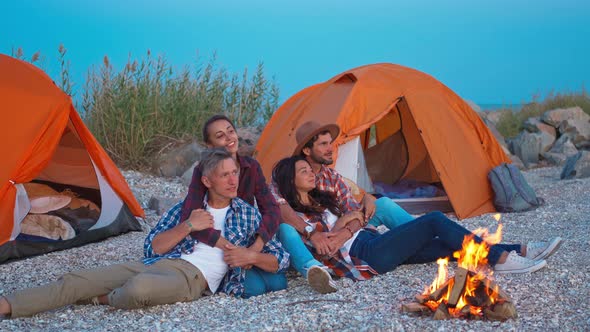 Two Cute Couples Embracing Each Other and Sitting By the Bonfire in Sea Camping at Evening and
