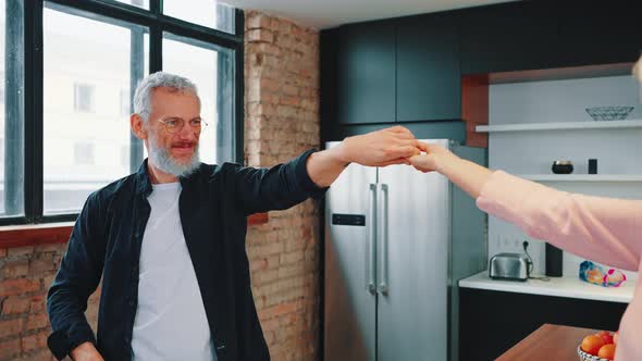 Excited Happy Mature Family Couple Dancing and Laughing in Kitchen Enjoying Good Health Wellbeing