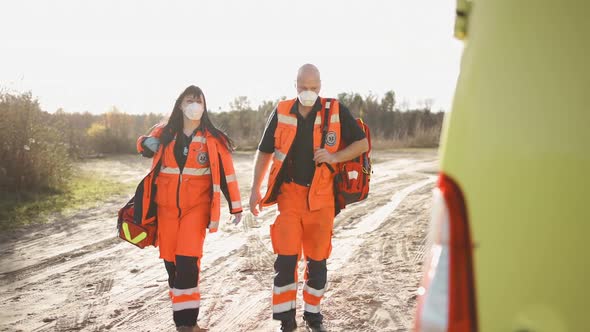 Two Paramedics in Full Equipment Walking Towards Ambulance Vehicle