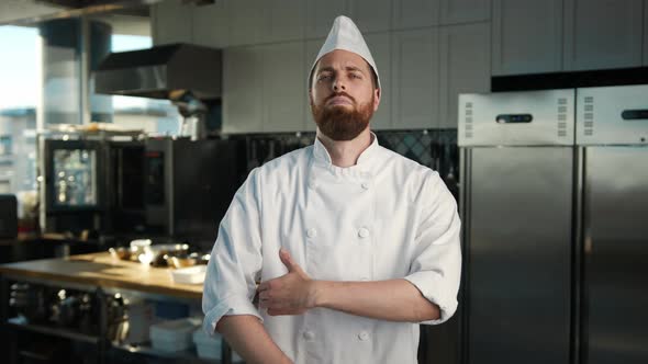 Professional kitchen, portrait: Male Chef folds his arms and looks at the camera