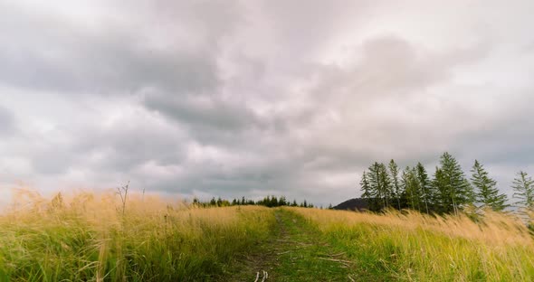 Clouds rolling over the tourist path on the rural meadow during summer season