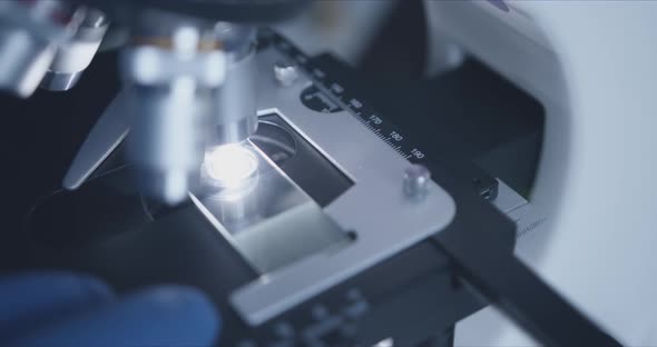 Sample Slide and Microscope with Metal Lens at Laboratory.