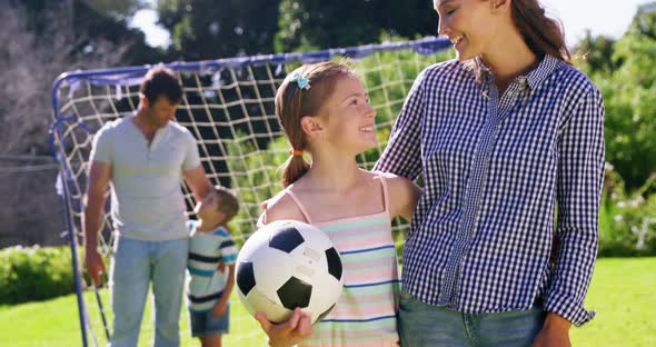 Portrait of smiling mother and daughter standing with football