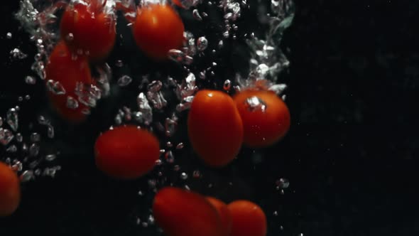 Closeup of Cherry Tomatoes Falling Into the Water in Slow Motion