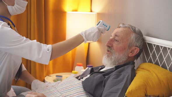 Young Female Doctor Applying Medical Device on Forehead of Senior Man